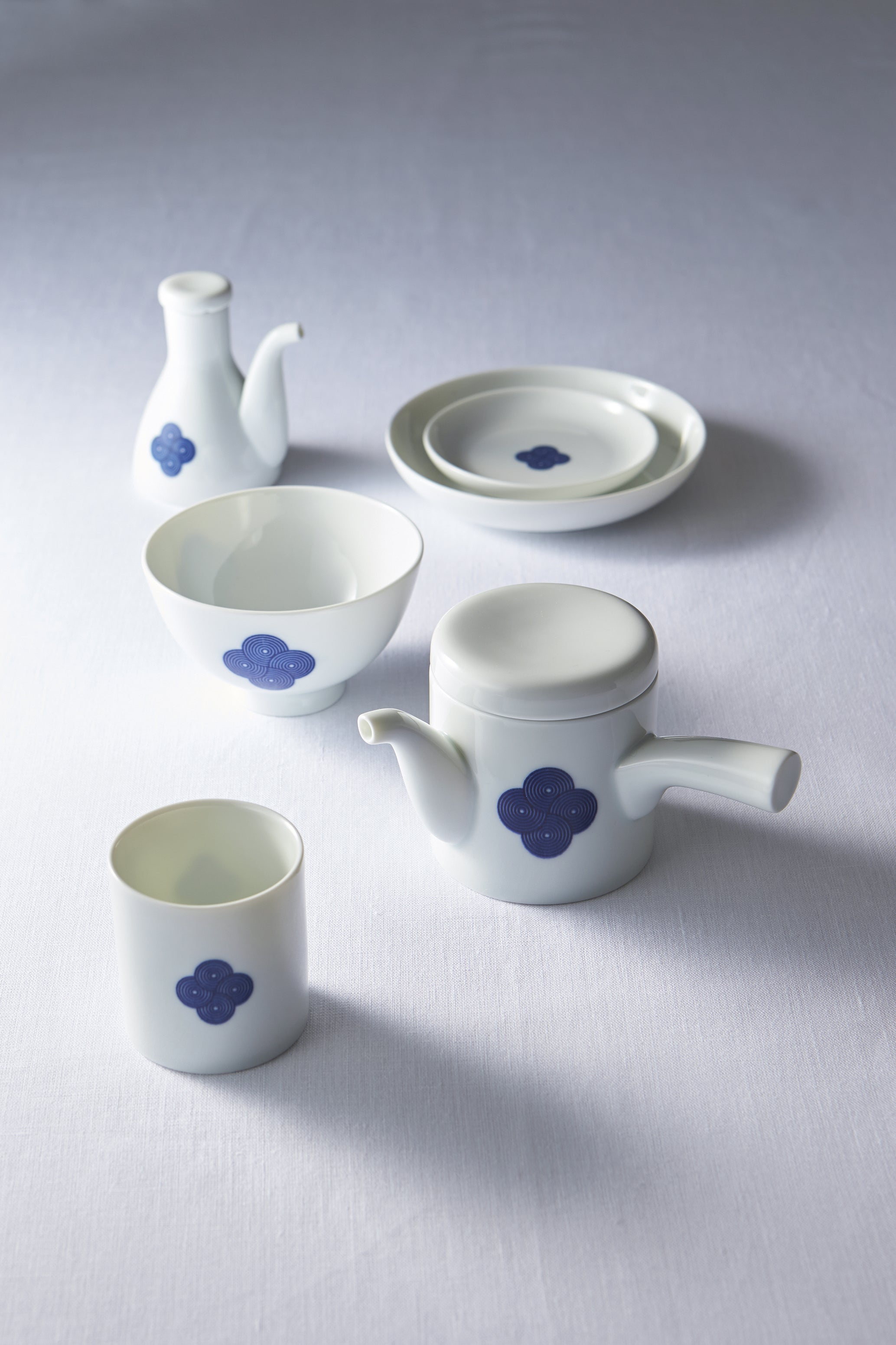 White Japanese porcelain **tea and dining set** with a **blue and white sometsuke floral swirl pattern**, showcasing the teapot, cup, bowl, and plate.