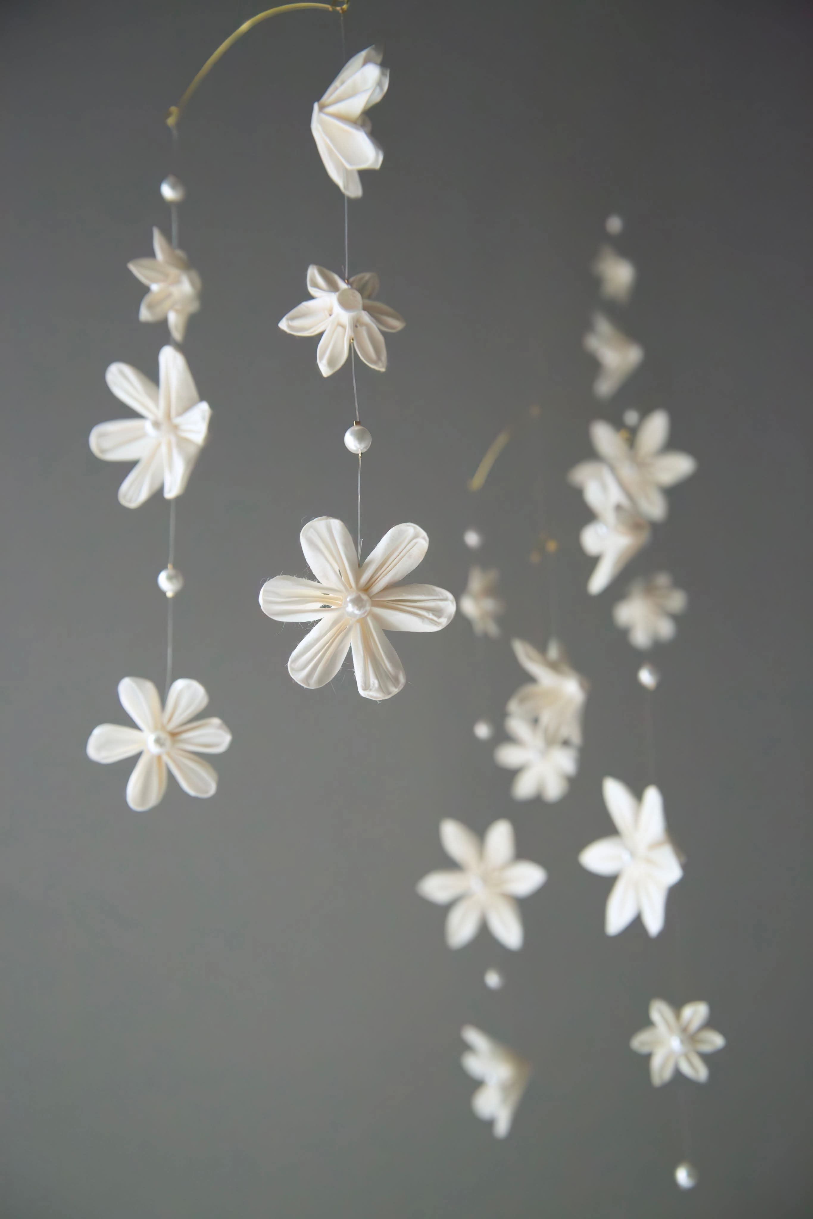 Kaminoka washi paper flower mobile hanging with white folded flowers against a gray wall