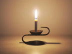 S-Shape Iron Stand with lit Warosoku candle in atmospheric warm lighting, lifestyle