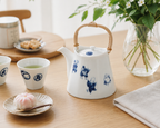 Shichifuku Dobin Teapot with sencha teacup, saucer and wagashi on wooden table, lifestyle scene