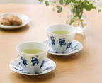 Shichifuku Saucer and sencha teacups in white porcelain with blue glaze on wooden table with green tea, lifestyle