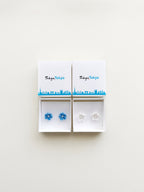 Pair of flower-shaped earrings in a Tokyo Tokyo branded box on a white background