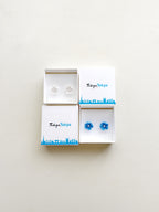 Two pairs of earrings in a 'Tokyo Tokyo' branded box on a light beige background
