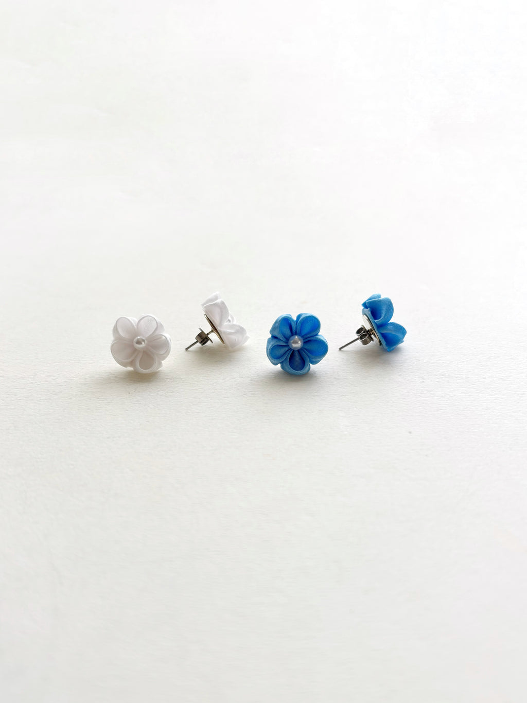 Pair of blue and white flower-shaped earrings on a light gray background