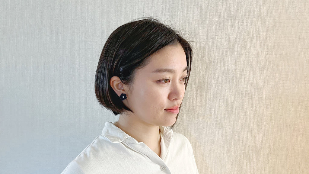 Woman with short black hair wearing a white shirt against a light background