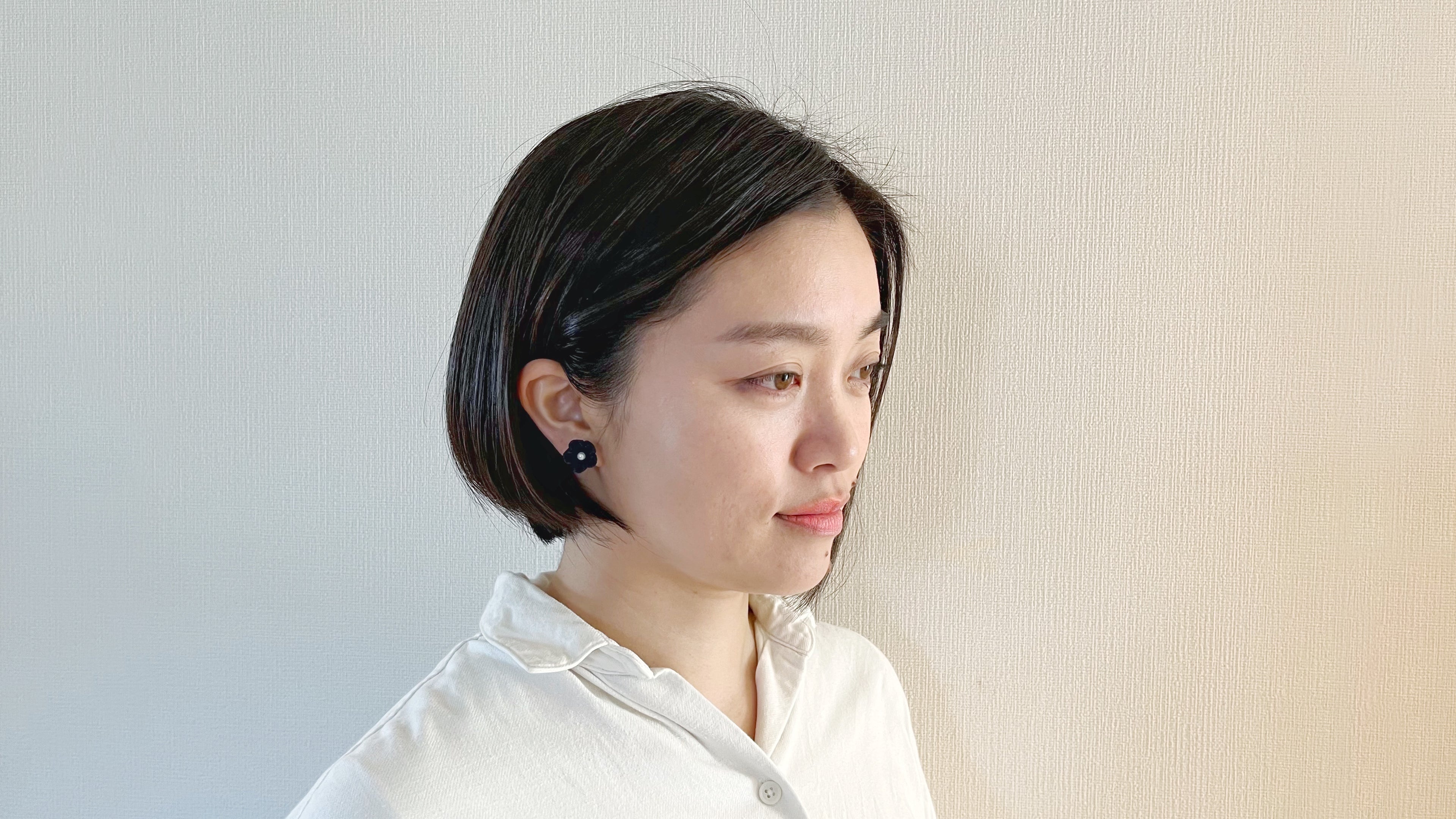Woman with short black hair wearing a white shirt against a light background