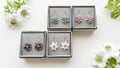 Floral earrings in gray boxes on a white background with flowers.
