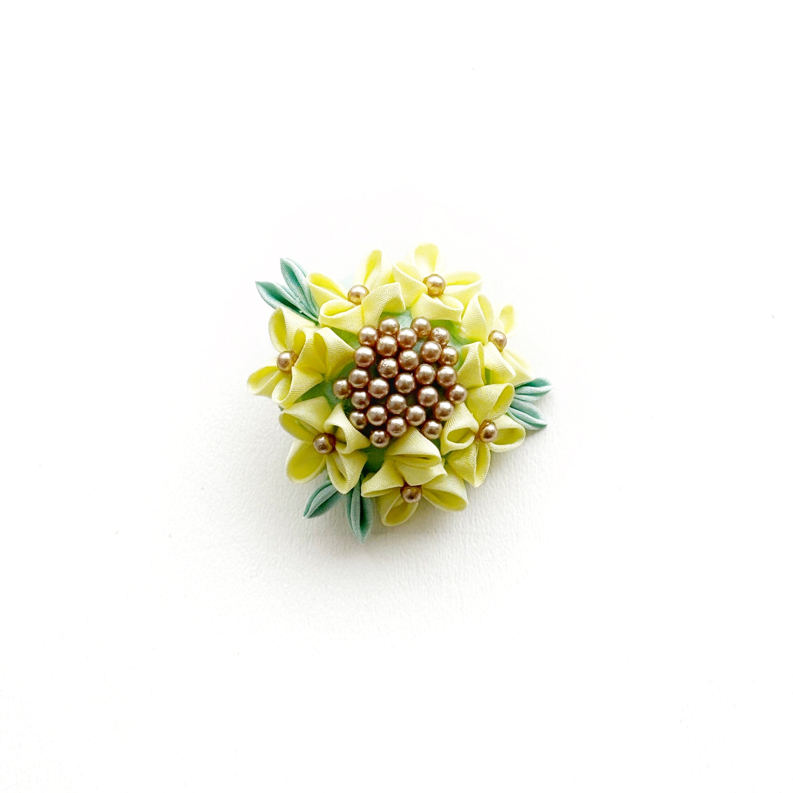 Decorative brooch with yellow flowers and a brown center on a white background