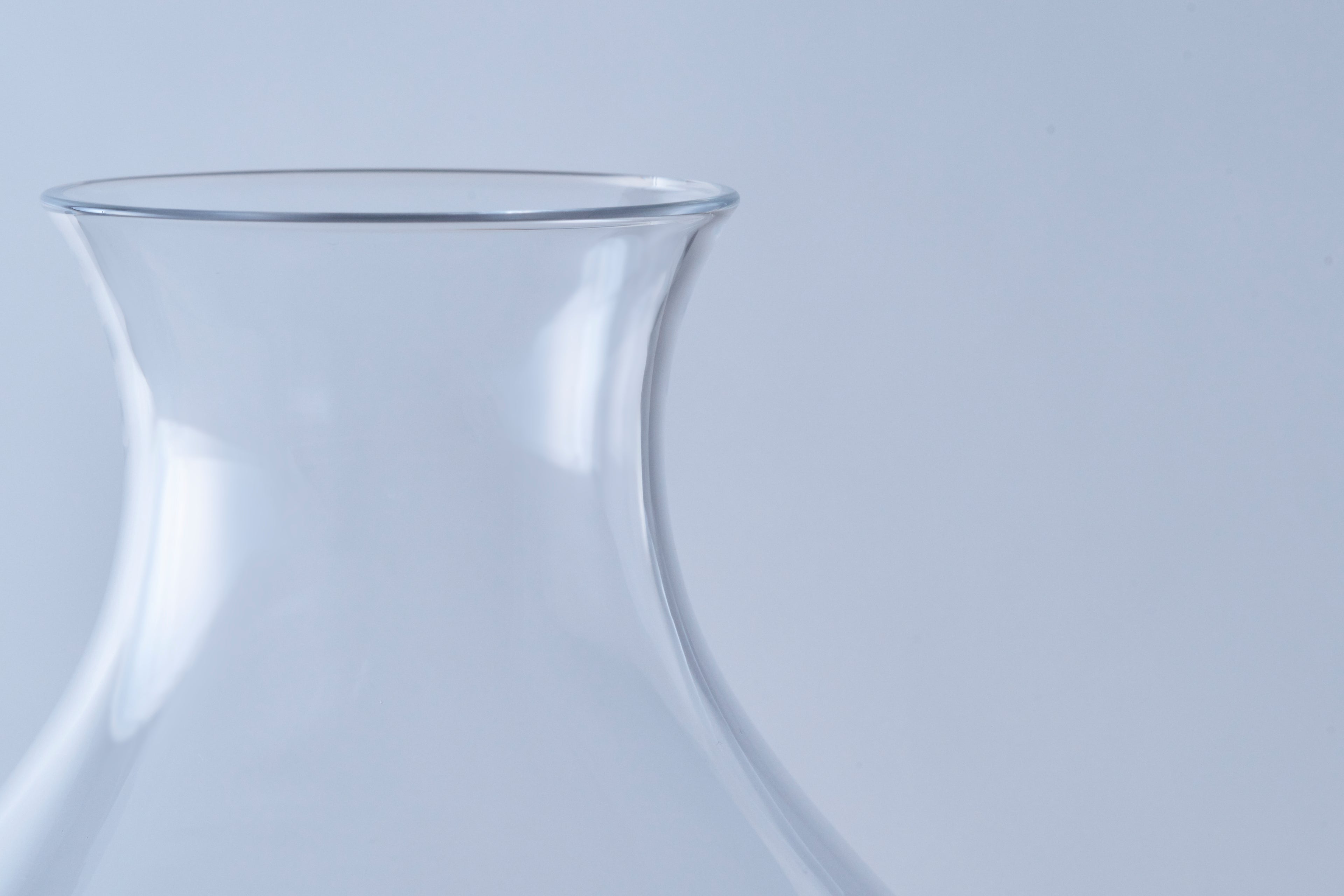 Detailed close-up of the smooth, tapered rim and elegant neck of a hand-blown artisanal beer glass.
