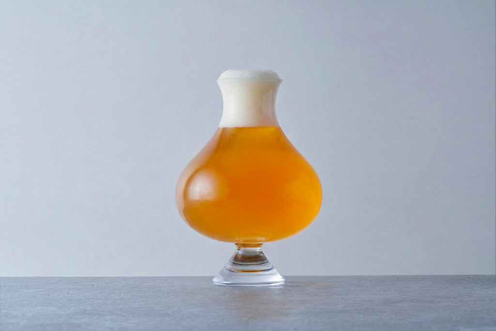 Handcrafted specialty beer glass filled with golden amber ale and a thick creamy white foam head, professional craft beer presentation.