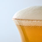 Handcrafted specialty beer glass filled with golden amber ale and a thick creamy white foam head, professional craft beer presentation.