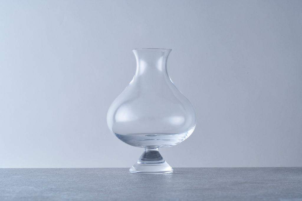 Clear thistle-style beer glass with a pedestal base and flared rim. Specialty glassware designed to enhance aromatics for Belgian ales, stouts, and craft beers.