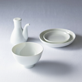 Minimalist set of **plain white Japanese porcelain dinnerware**, featuring a bowl, stacked plates, and a soy sauce pitcher.