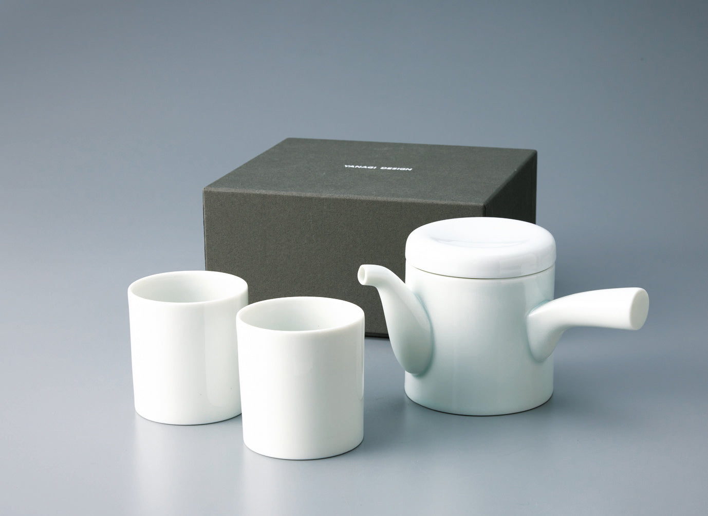 Complete Japanese tea set featuring one white porcelain teapot and two matching Yunomi cups, displayed with the dark gray gift box.